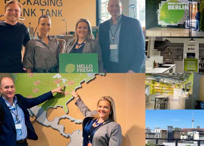 Four people smiling in a HelloFresh event area with a green HelloFresh sign in the foreground.