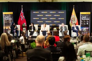 Brampton_Food and Bev Summit_D85_8624 - Invest Brampton | Brampton Economic Development Panel discussion on stage with five speakers, Invest Brampton banners, and audience in foreground.