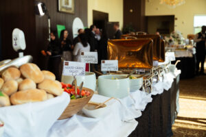 Brampton_Food and Bev Summit_Z62_9713 - Invest Brampton | Brampton Economic Development Buffet table with bowls of salads and pastries, labeled chickpea and mixed greens as guests mingle in the background